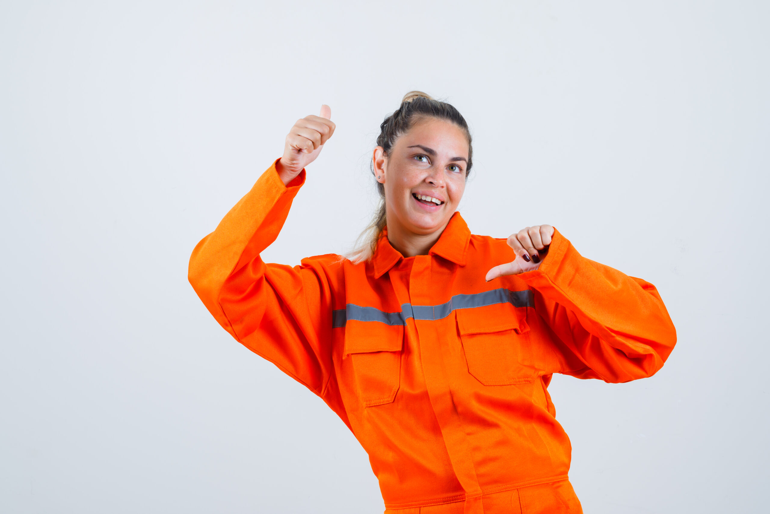 Uma Jovem com uniforme de trabalhador, cor laranja, apontando para cima e para baixo e olhando vista frontal.